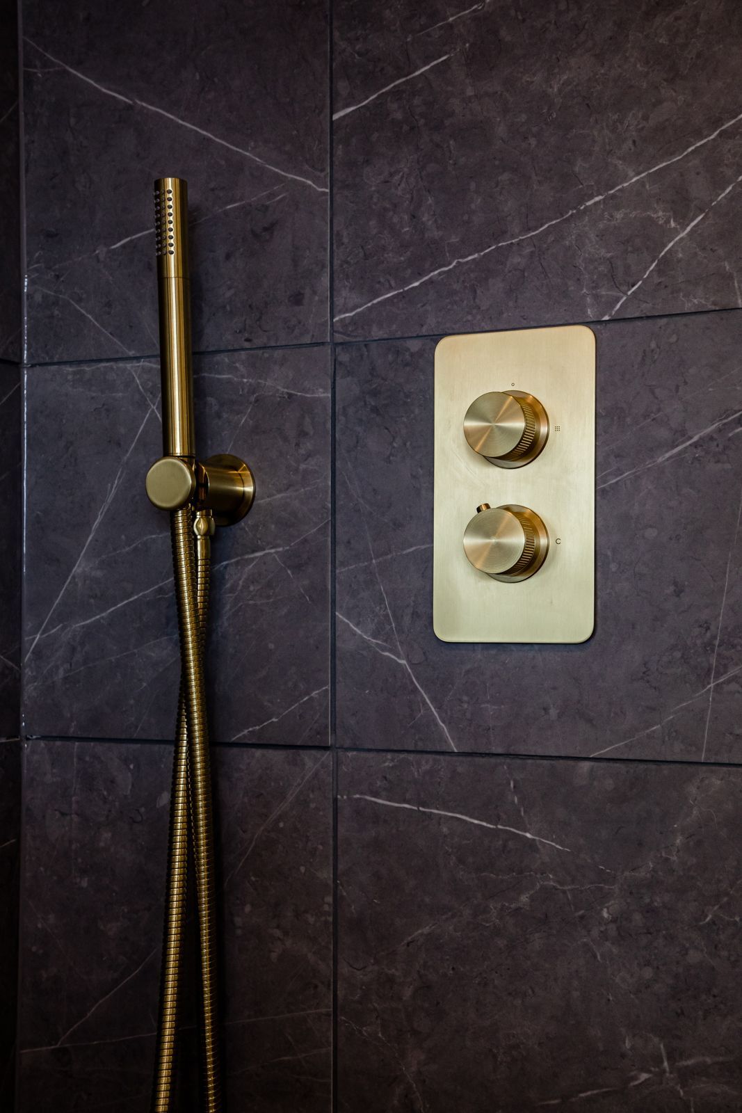 A close up of a shower head on a tiled wall.