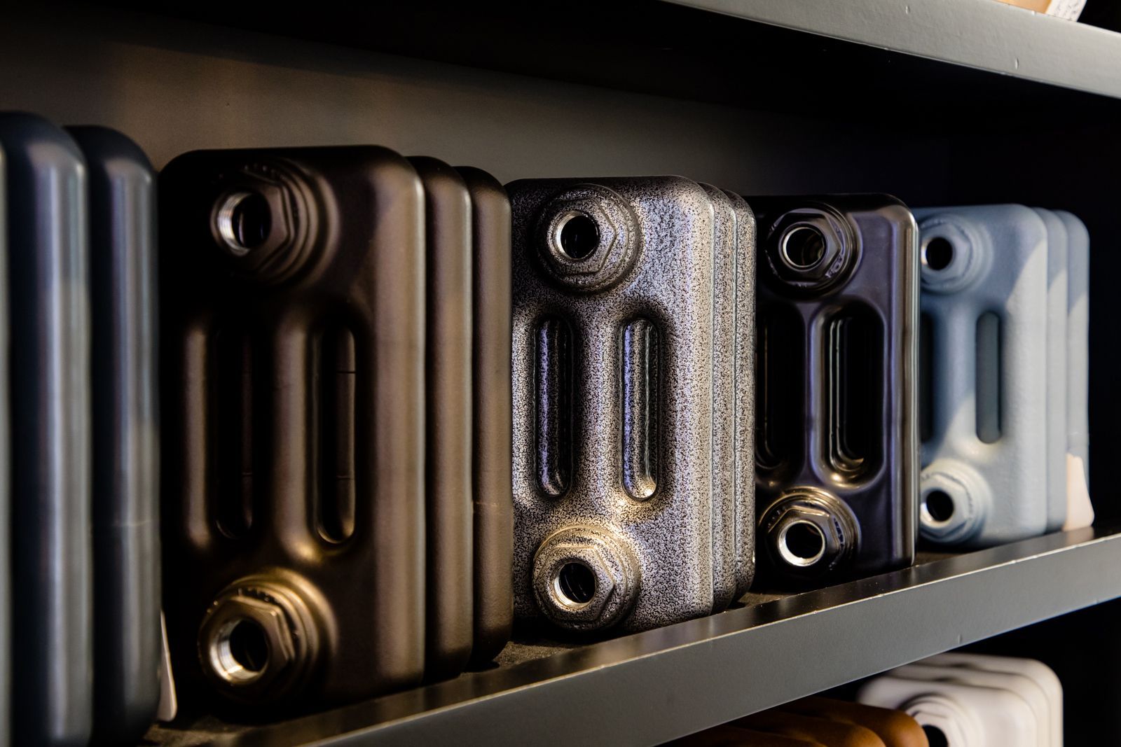 A row of radiators are lined up on a shelf.