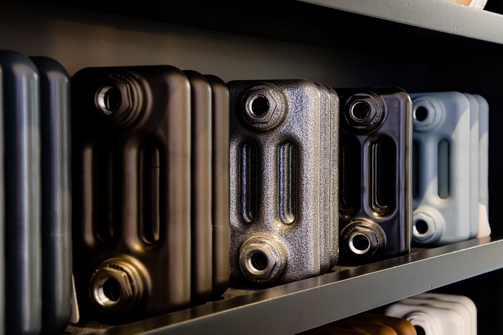 A row of radiators are lined up on a shelf.