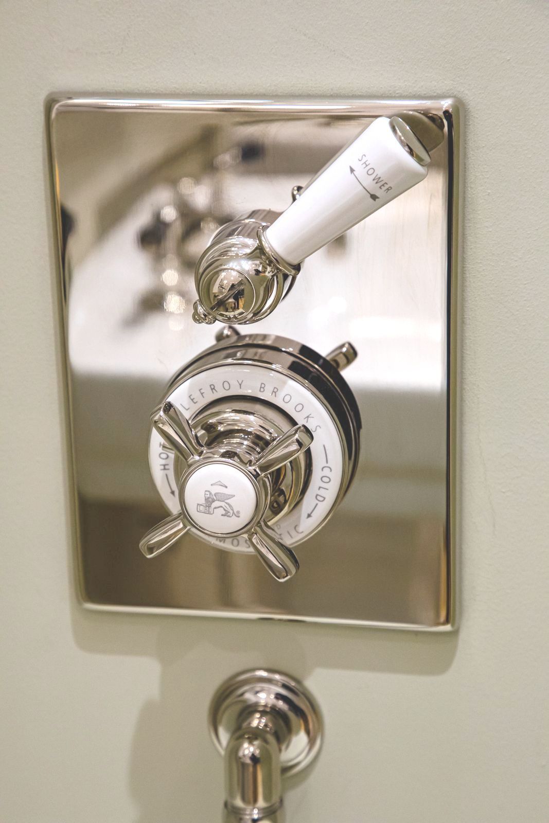 A close up of a chrome shower faucet with a white handle.