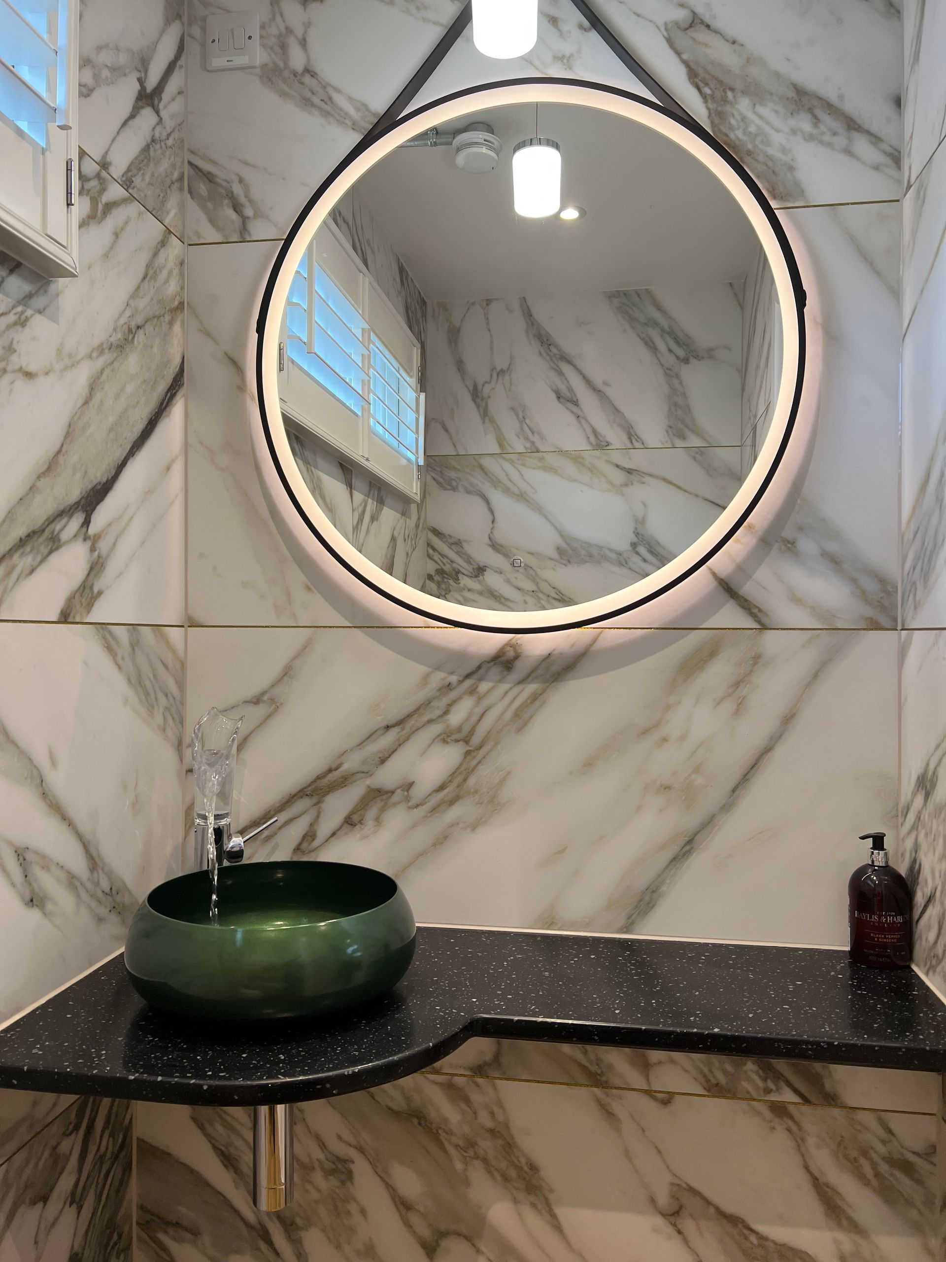 A bathroom with a green sink and a round mirror