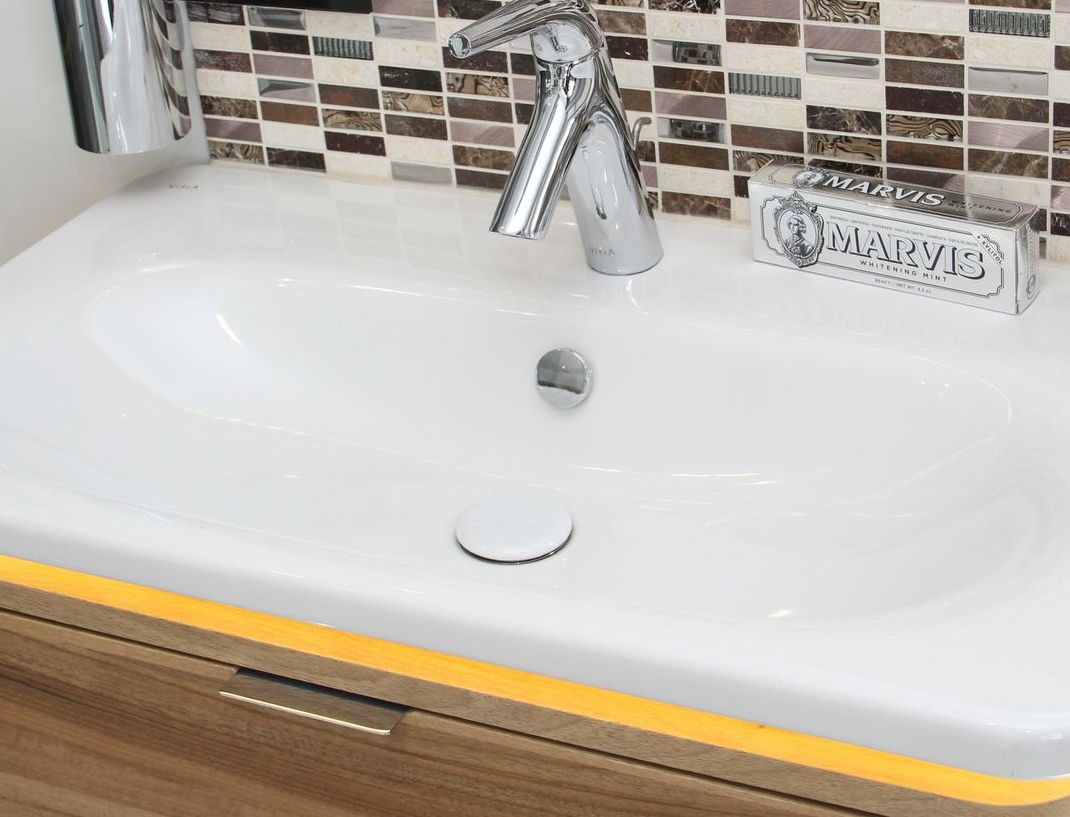 A bathroom sink with a faucet and a wooden cabinet.