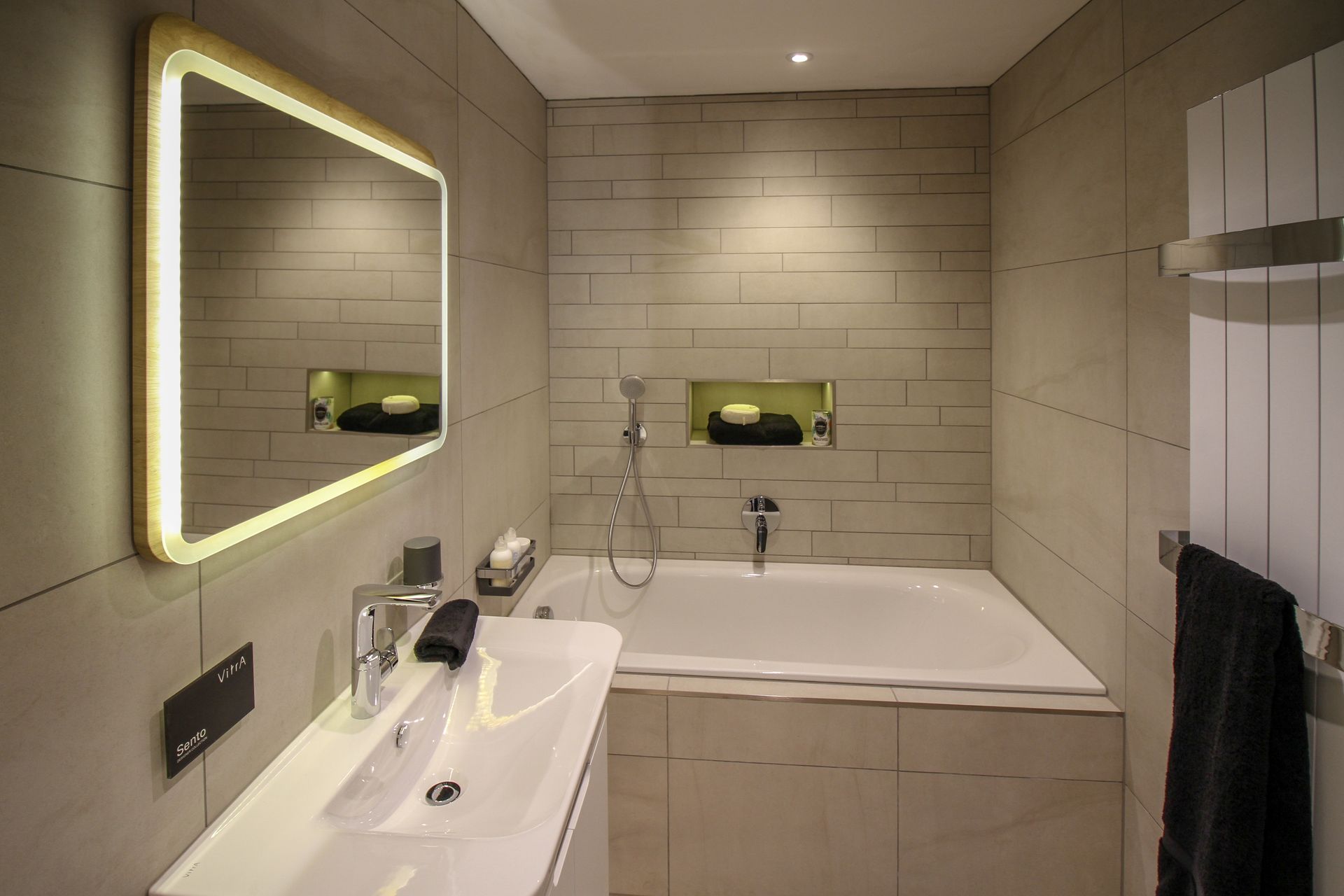 A bathroom with a bathtub , sink , mirror and towel rack.