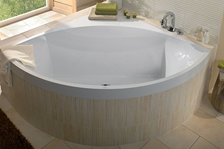 A white bathtub is sitting in a bathroom next to a window.