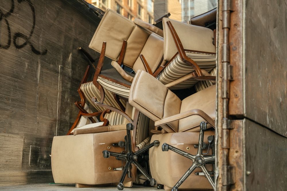 Stacked wooden chairs piled in a narrow alley against concrete walls