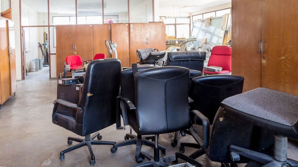 Office space with several black chairs, red seat cushions, and wooden partitions around a cluttered desk area