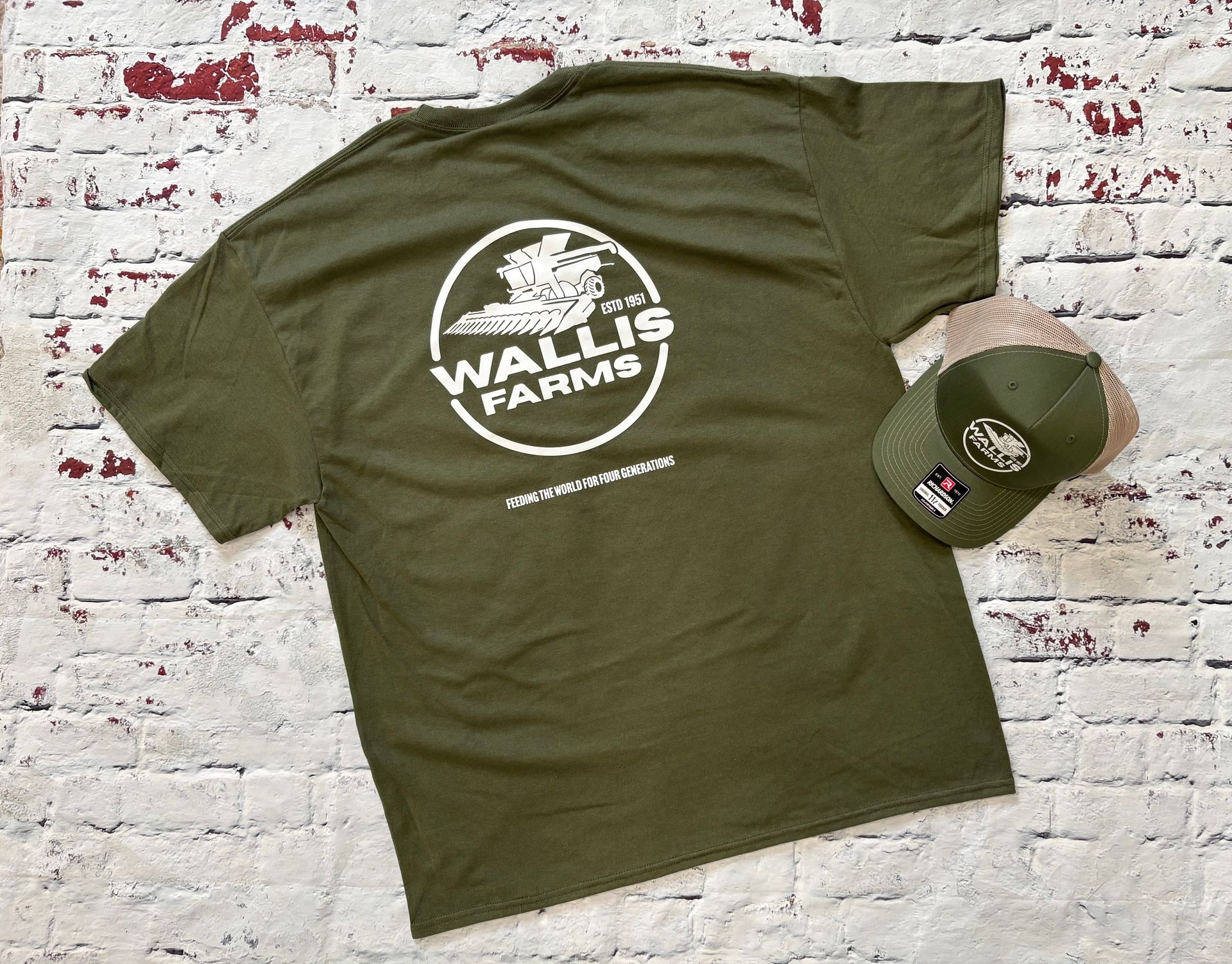 A green wallis farms t-shirt and hat are laying on a white brick floor - Princeton, IN - Make Your Mark