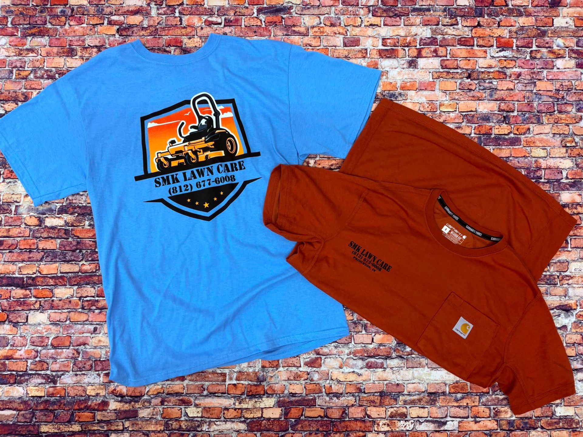 A blue t-shirt and an orange t-shirt are on a brick wall