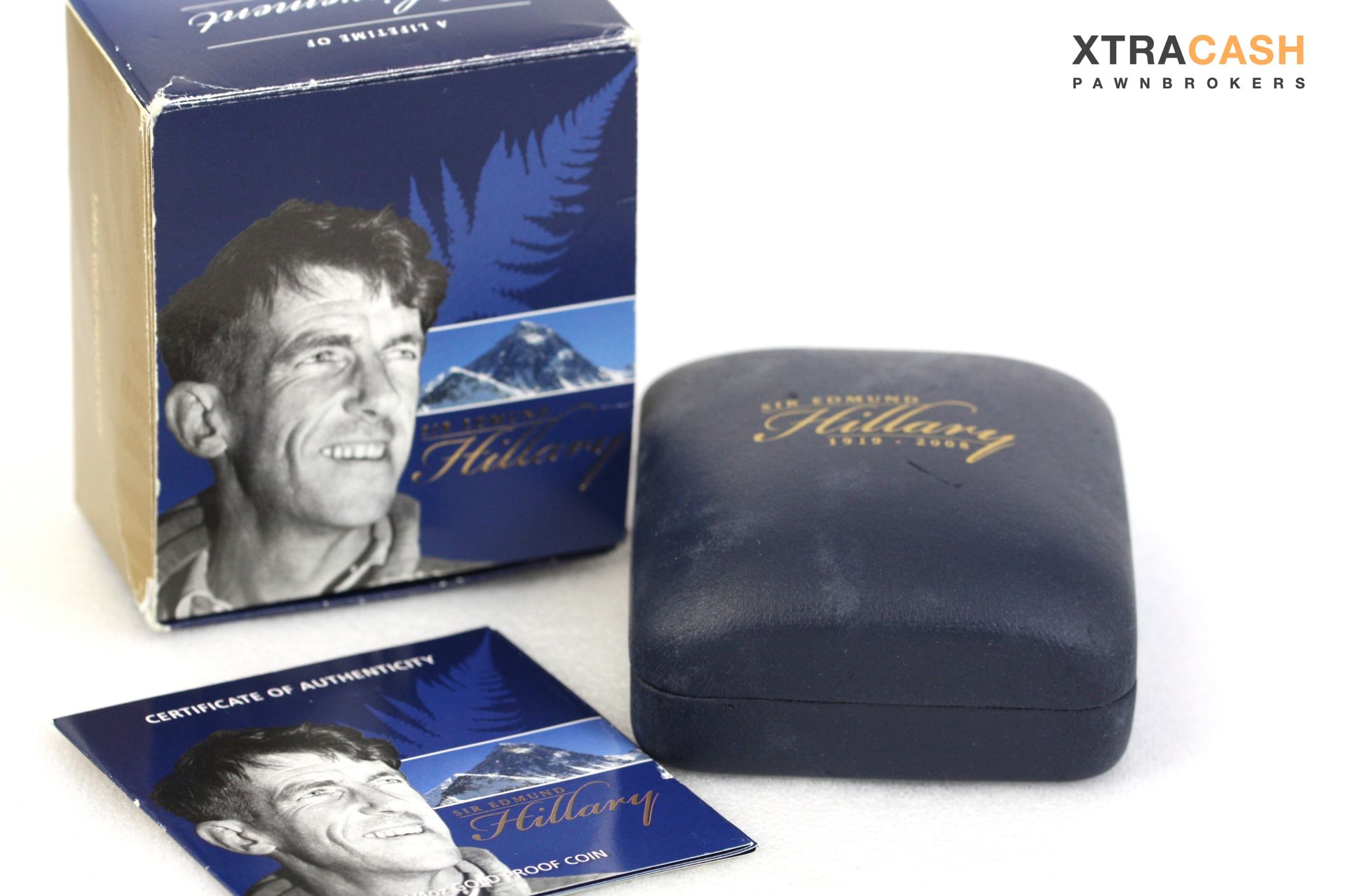Blue commemorative coin set with a gold medallion in a velvet case and matching box on a white surface