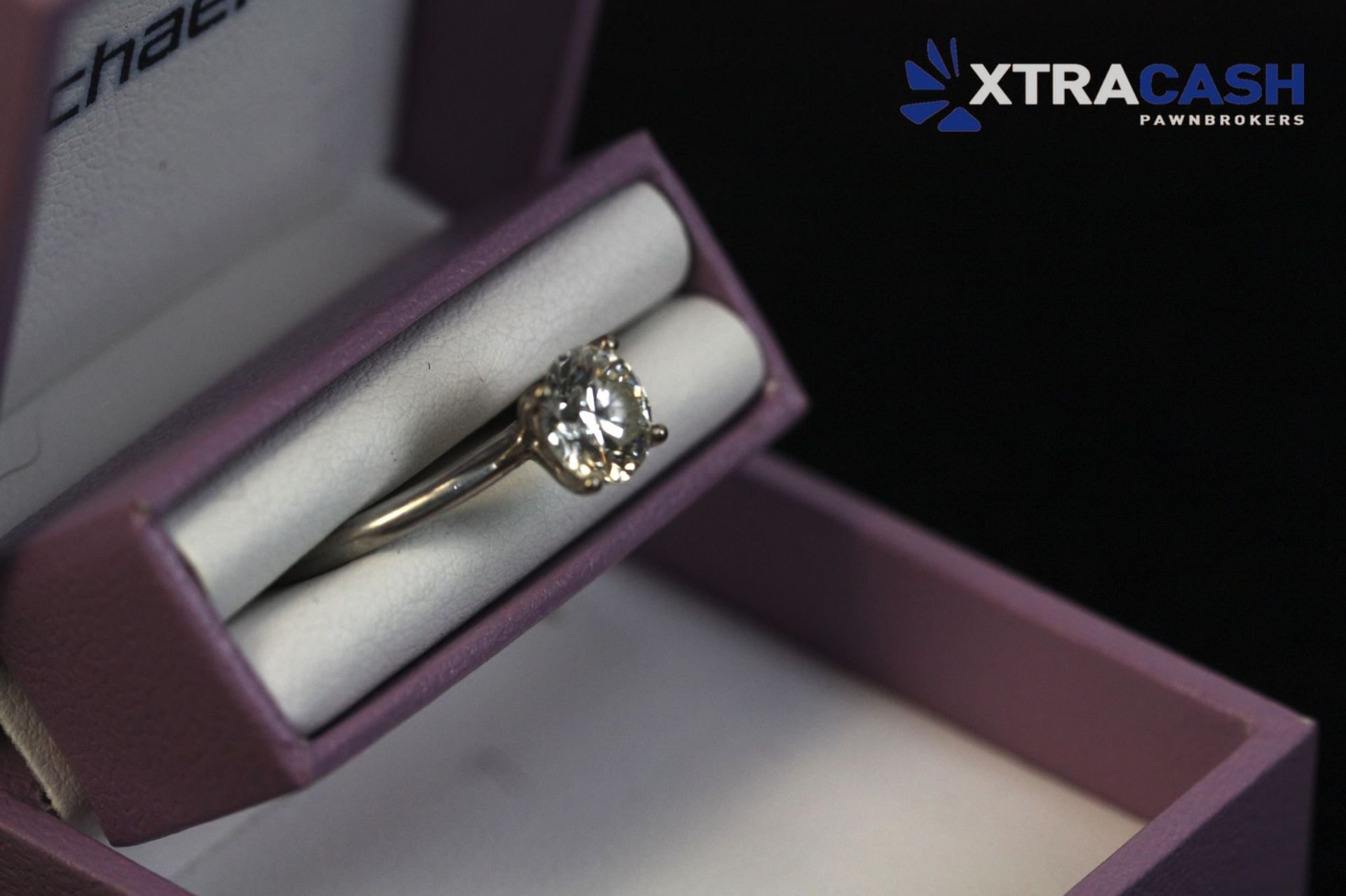 Purple jewelry box displaying a silver ring on a white cushion, with Michael Hill branding inside the lid