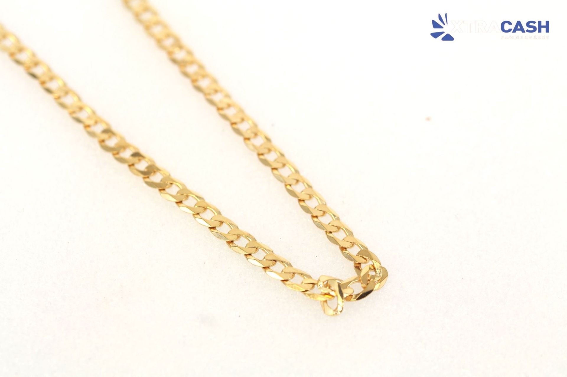 Gold chain necklace on a white background with a small clasp at the bottom right