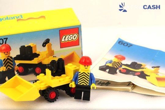 LEGO worker driving a yellow construction loader with a red hard hat and black wheels