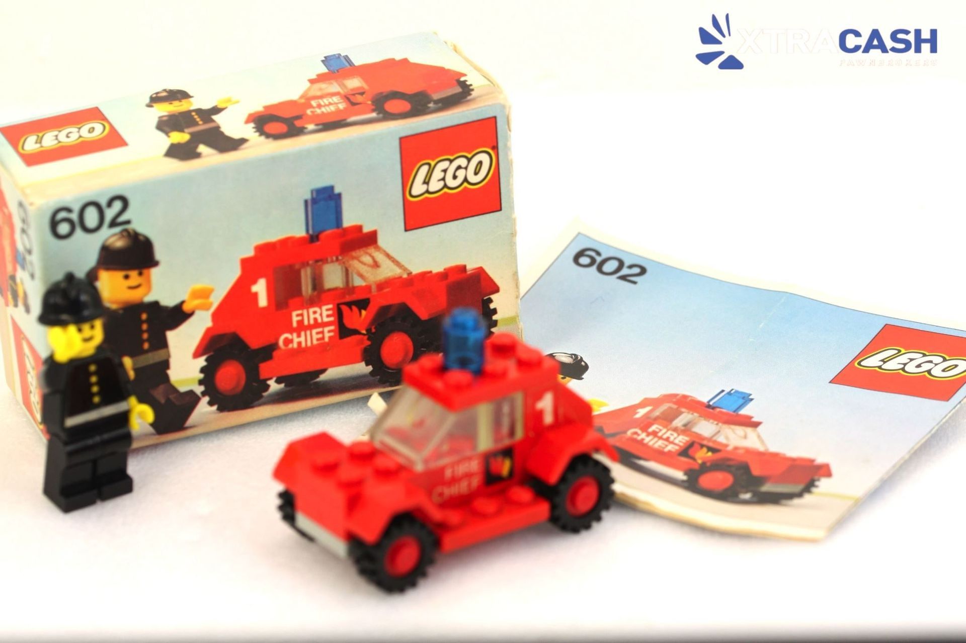 LEGO firefighter minifigure beside red fire chief truck with blue light