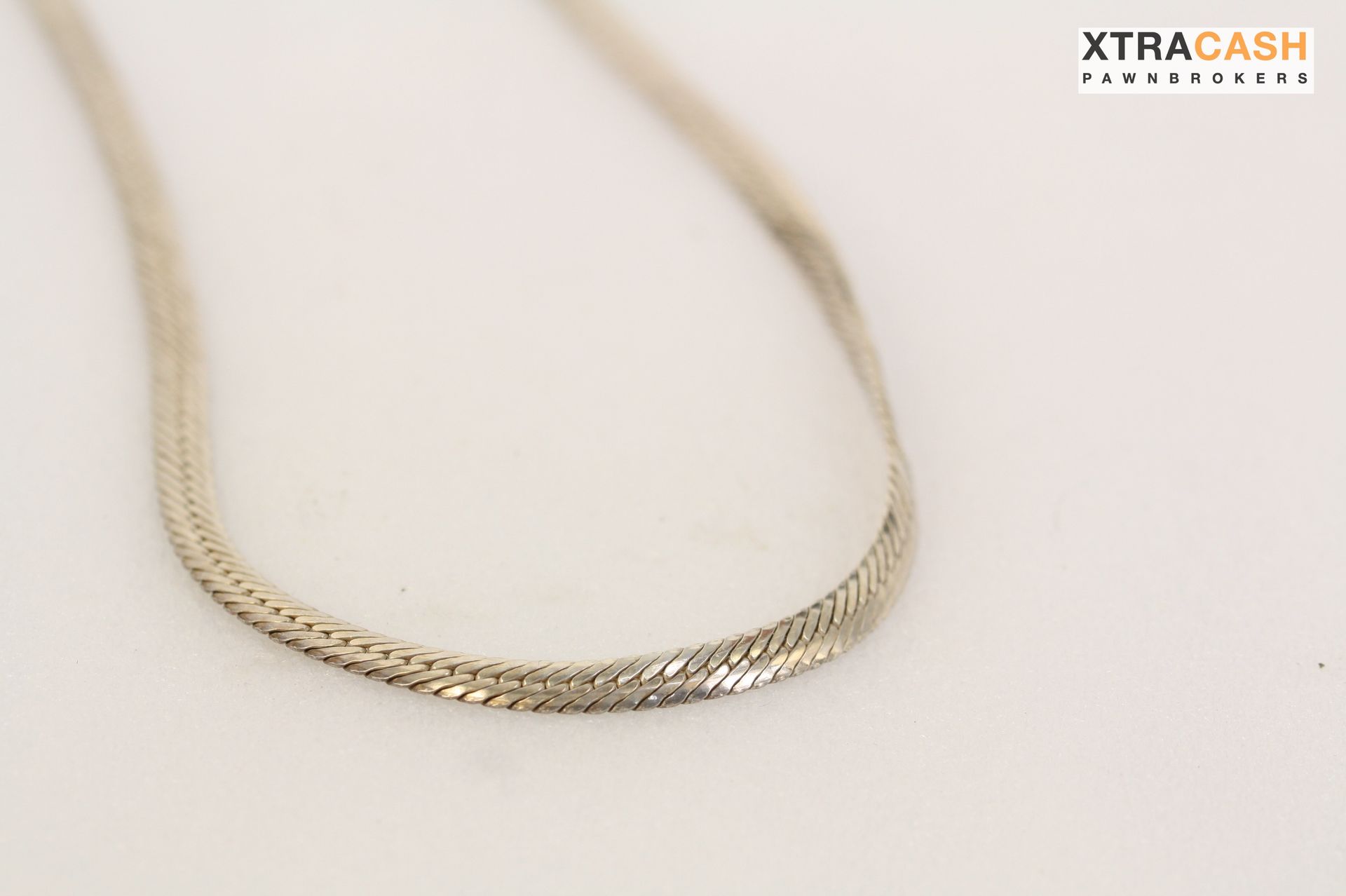 Silver chain necklace laid in a loop on a light background