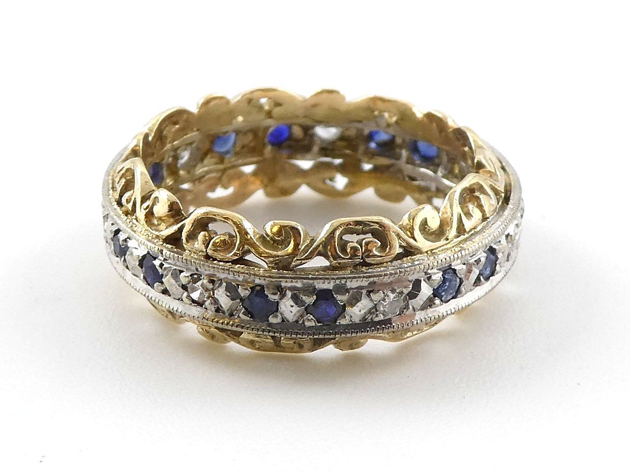 Gold and silver jeweled ring with blue stones on a white background