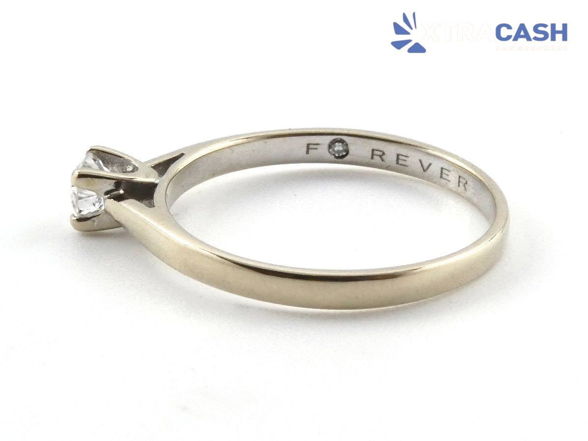 Silver ring with a small square diamond solitaire on a white background