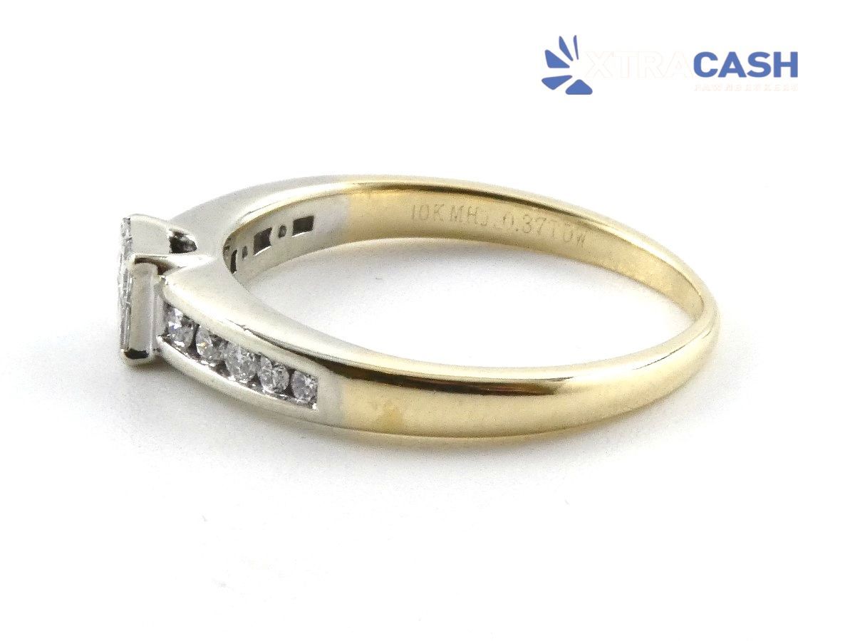 Gold ring with square center stone and small side stones on white background