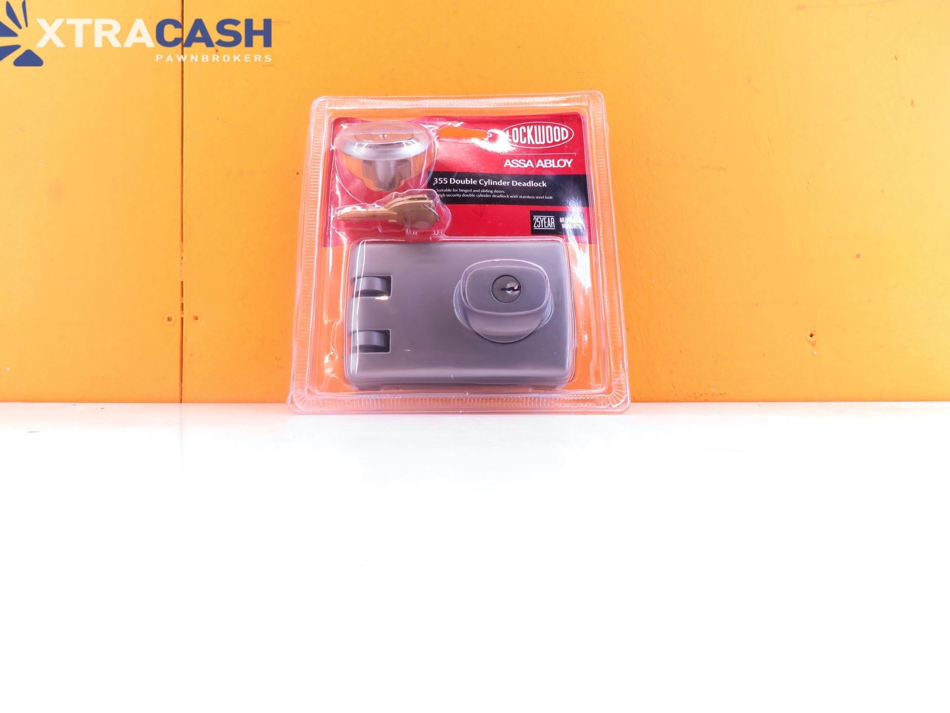 Clear plastic pack of XTRACASH safe deposit pouch on orange background