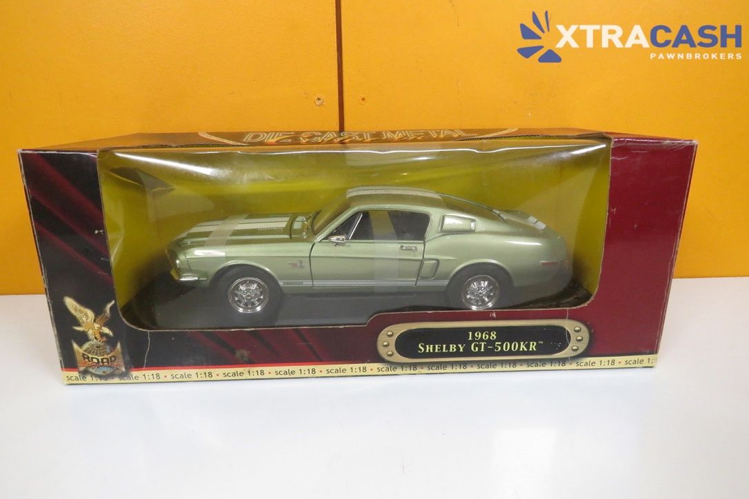 Toy silver vintage car in a red-and-gold display box on a white background