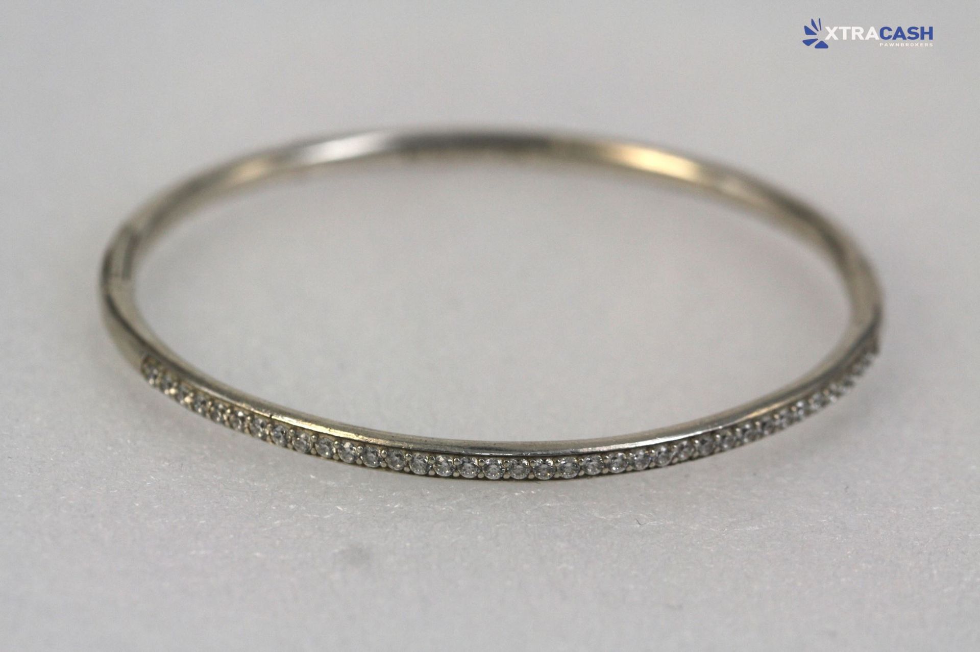 Thin silver textured bangle bracelet on a light gray background