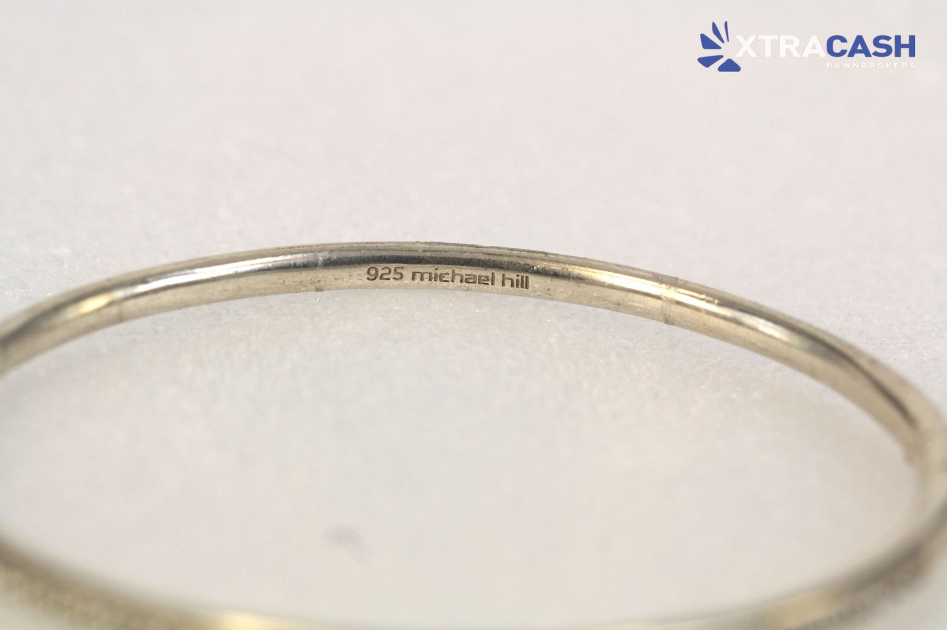 Thin silver textured bangle bracelet on a light gray background