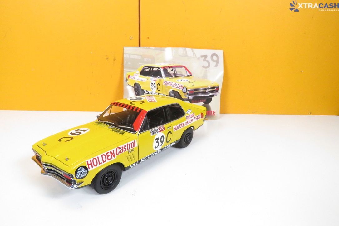 Yellow toy race car displayed beside its box on a white surface against a yellow background