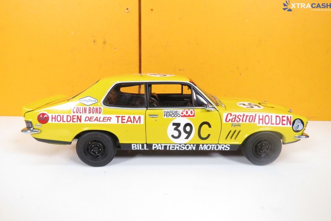 Yellow toy race car displayed beside its box on a white surface against a yellow background