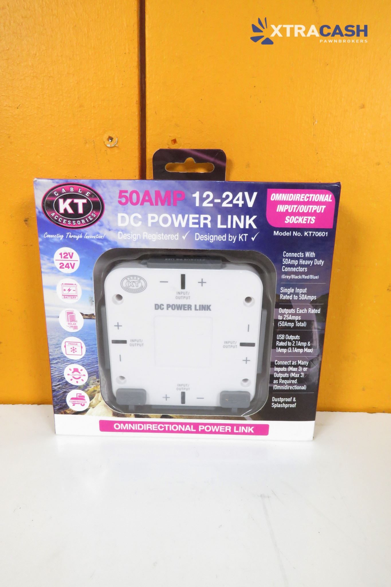 KT 50AMP 12-24V DC power link box in black packaging on a white shelf against an orange wall