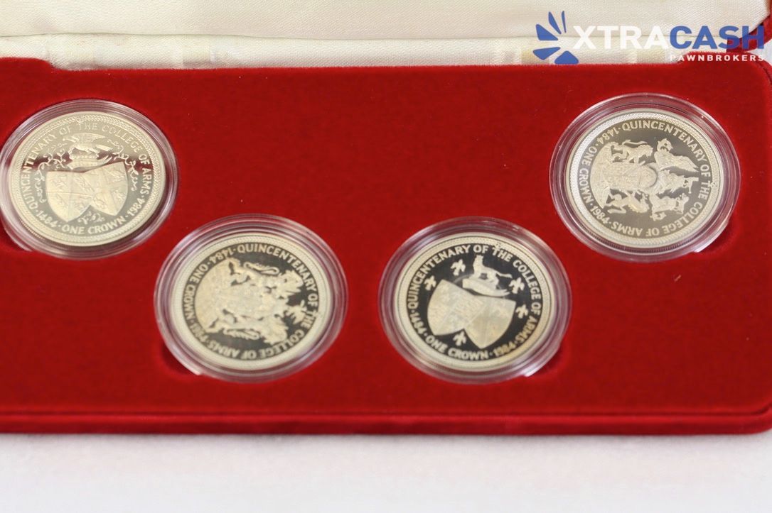 Red display case holding four silver commemorative coins on a white background