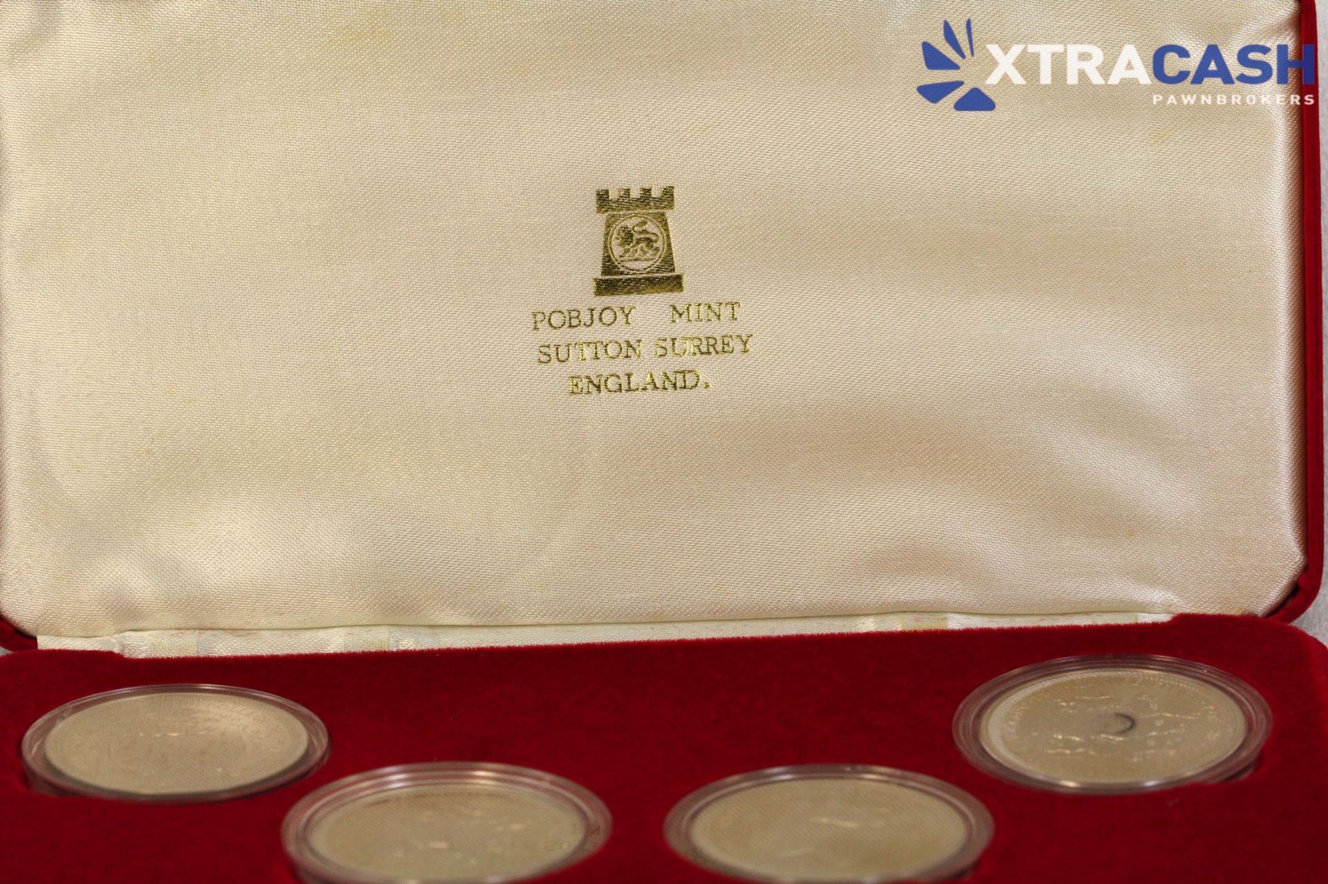 Red display case holding four silver commemorative coins on a white background