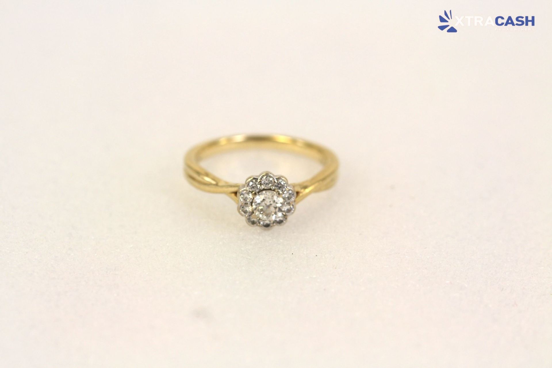 Gold ring with a round diamond cluster setting on a light background