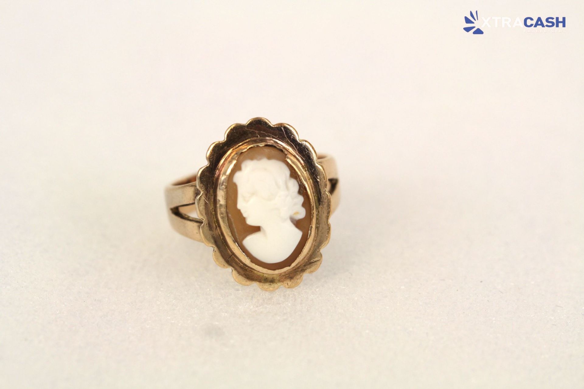 Gold ring with a white cameo profile on a display stand