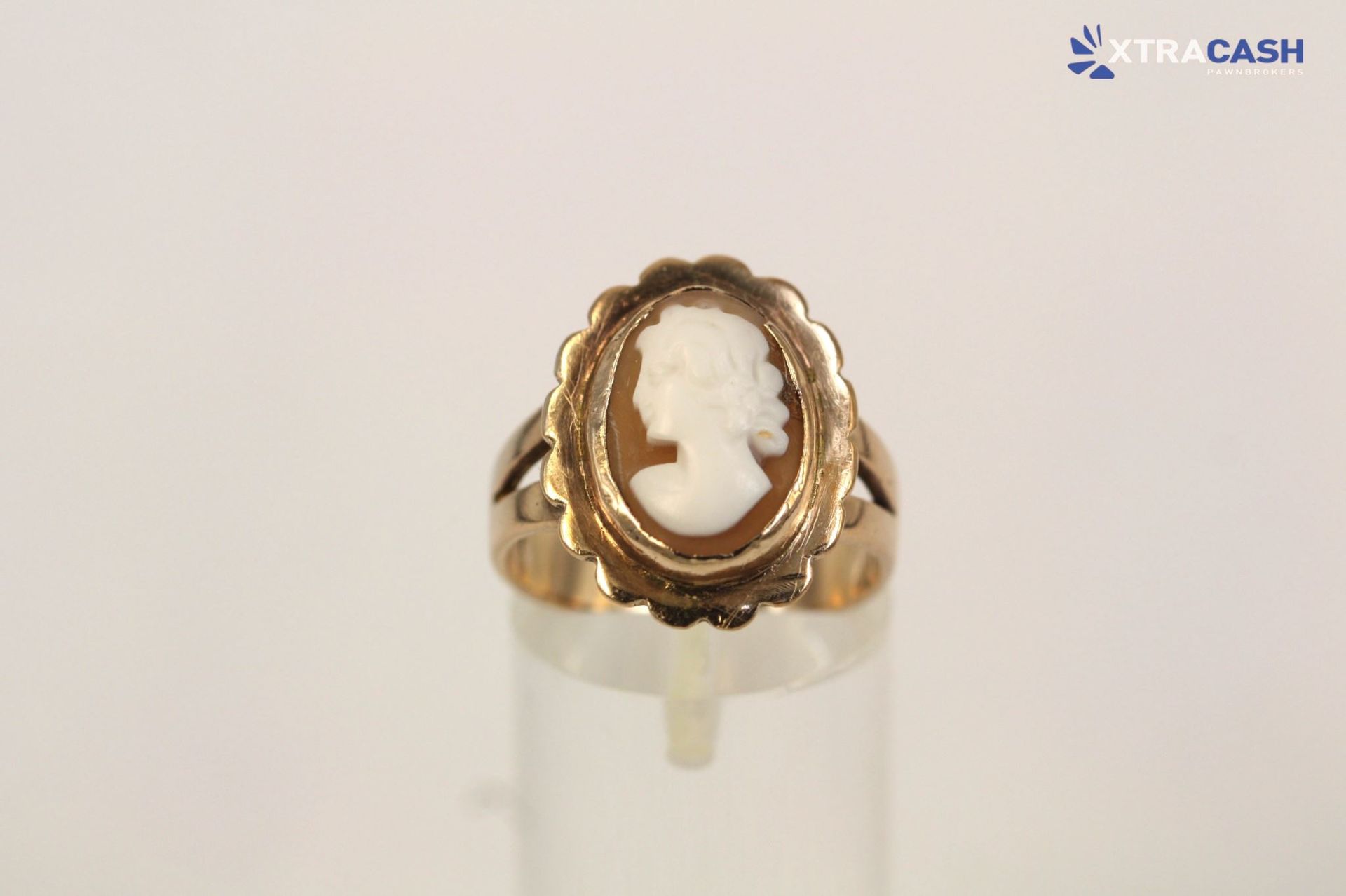 Gold ring with a white cameo profile on a display stand