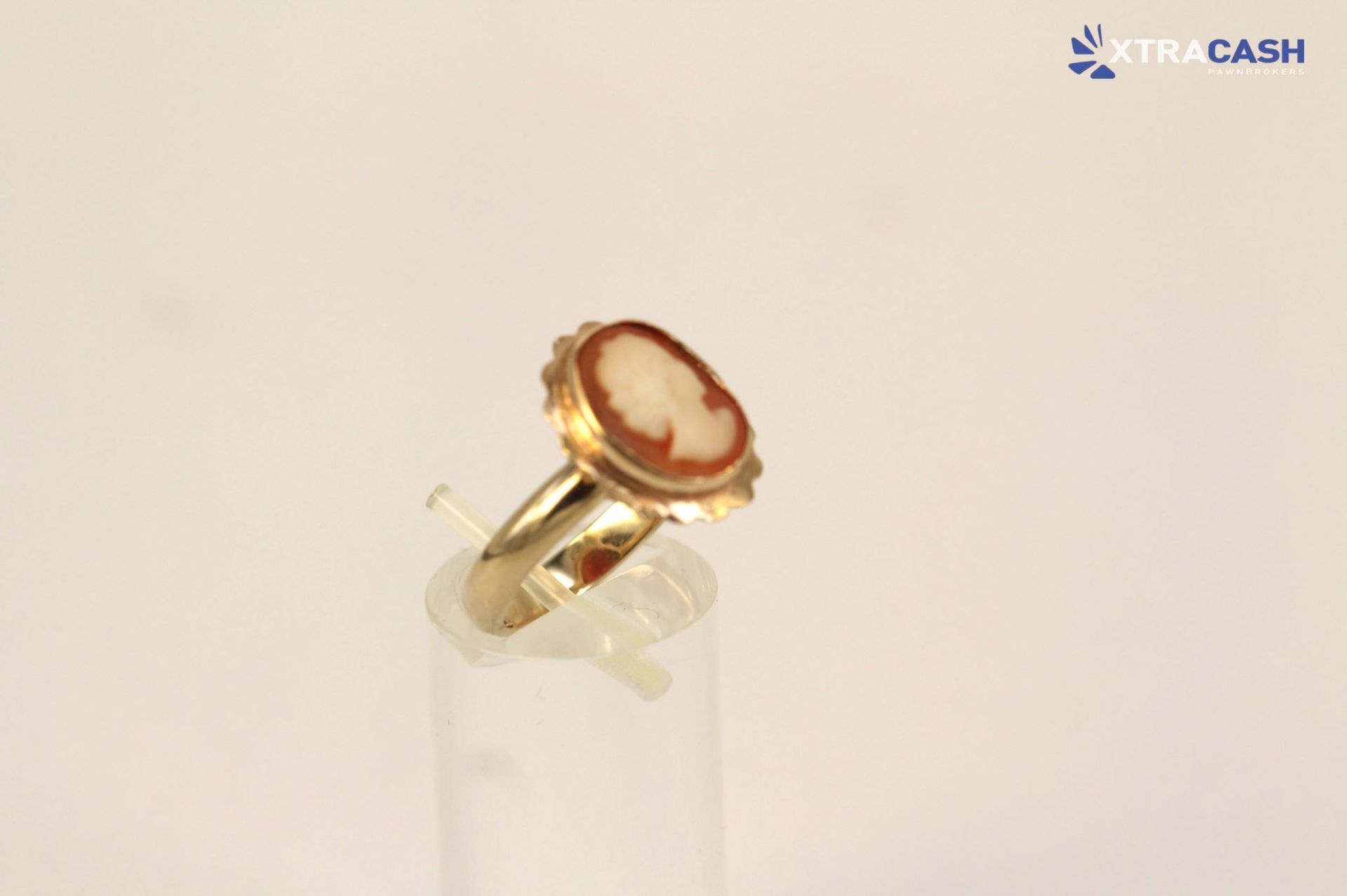 Gold ring with a red cameo profile on a clear display stand