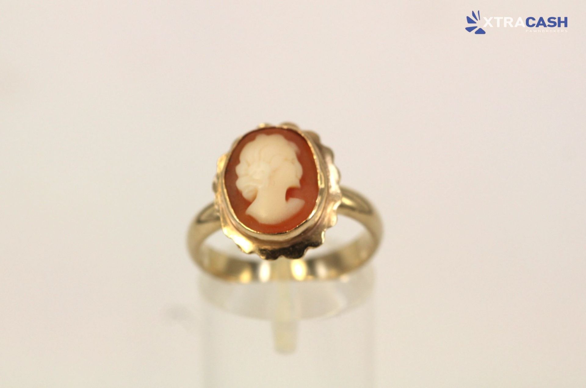 Gold ring with a red cameo profile on a clear display stand