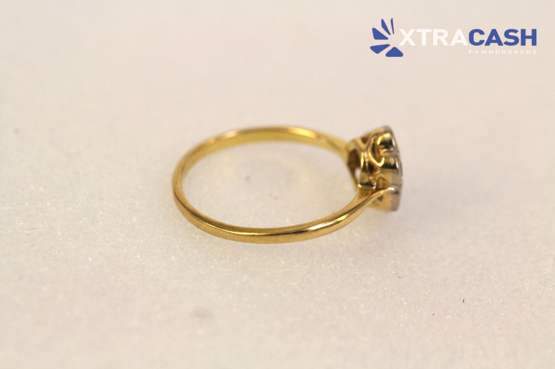 Gold ring with a flower-shaped diamond cluster on a light background
