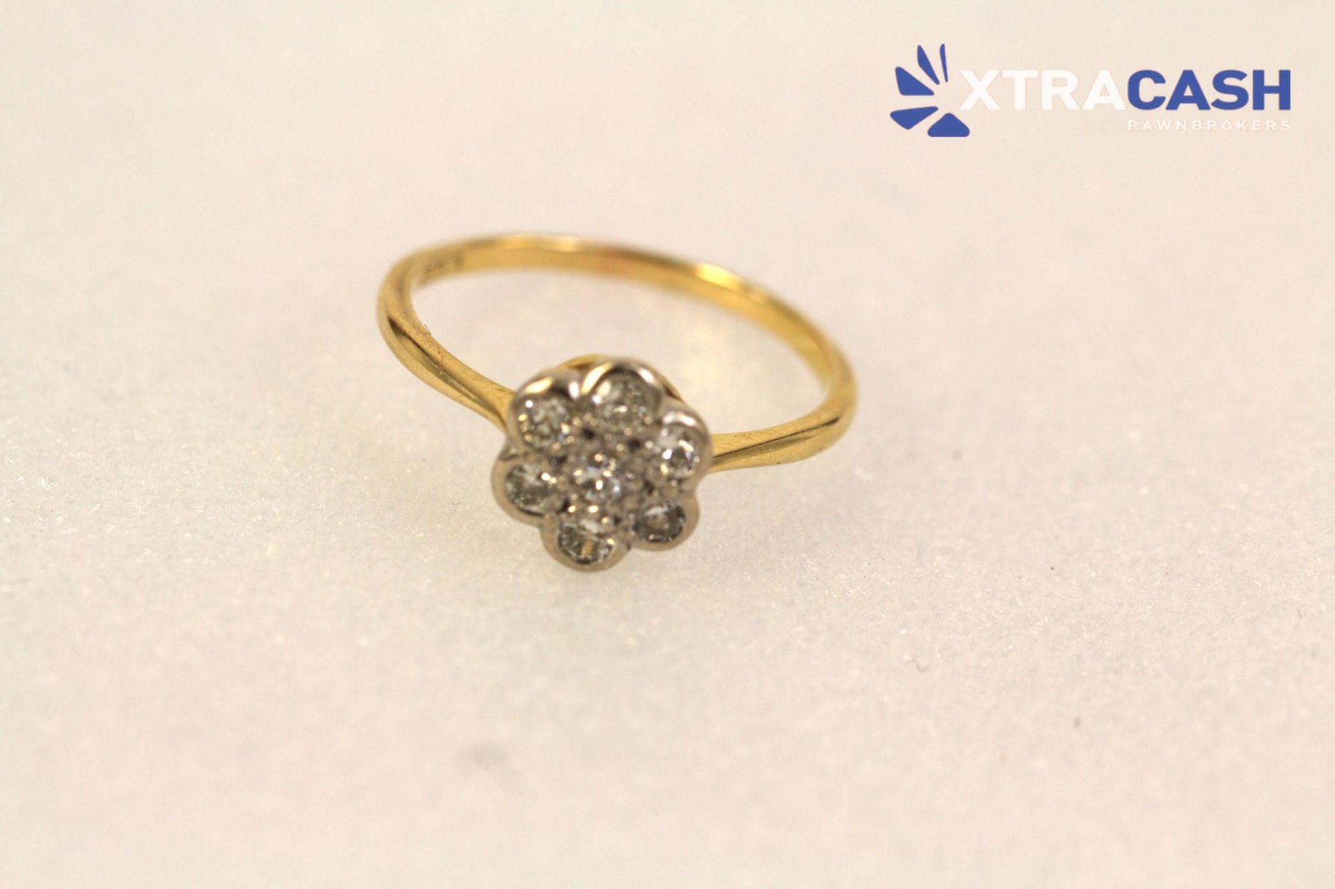 Gold ring with a flower-shaped diamond cluster on a light background