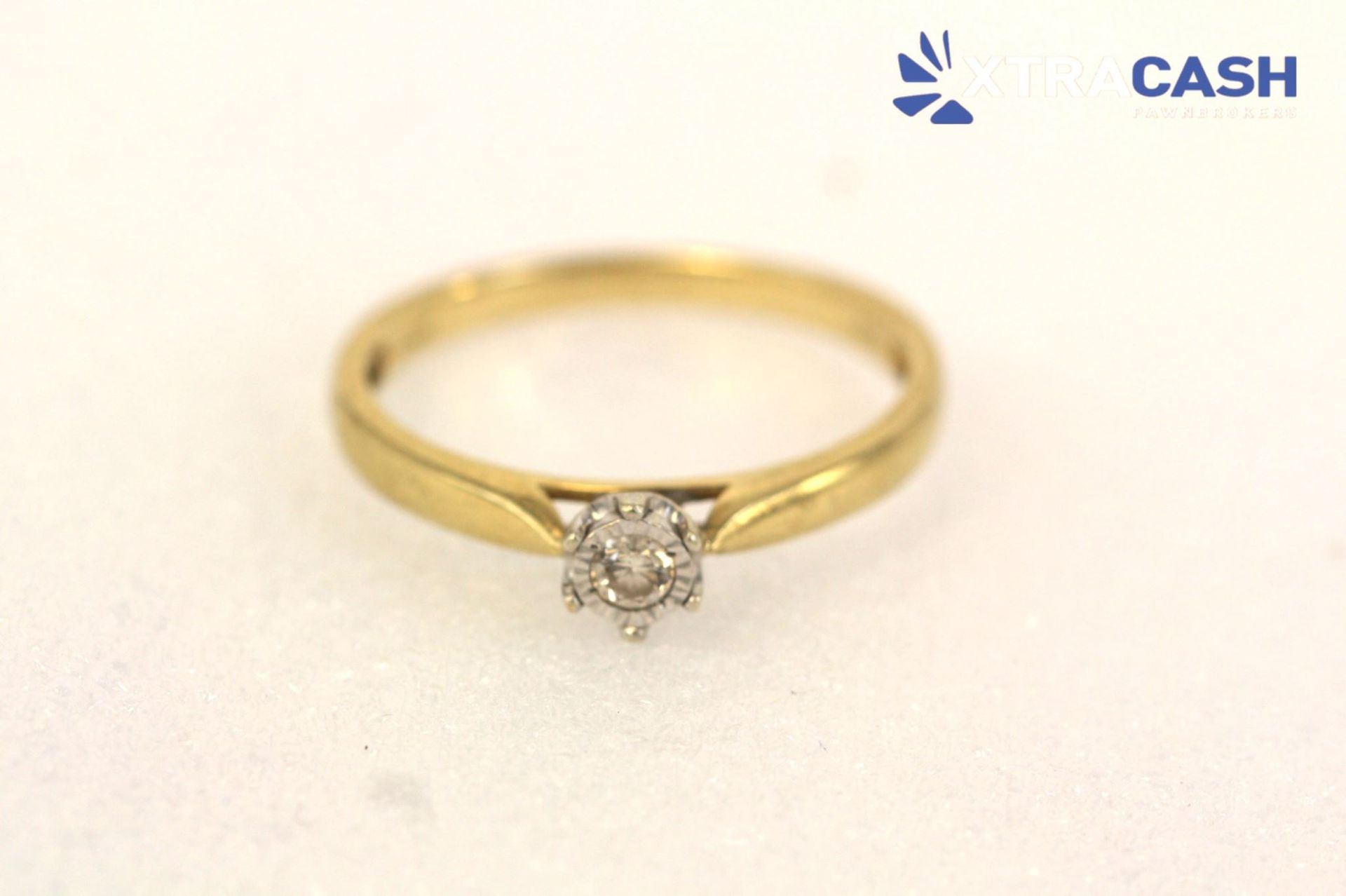 Gold ring with a small diamond on a light background