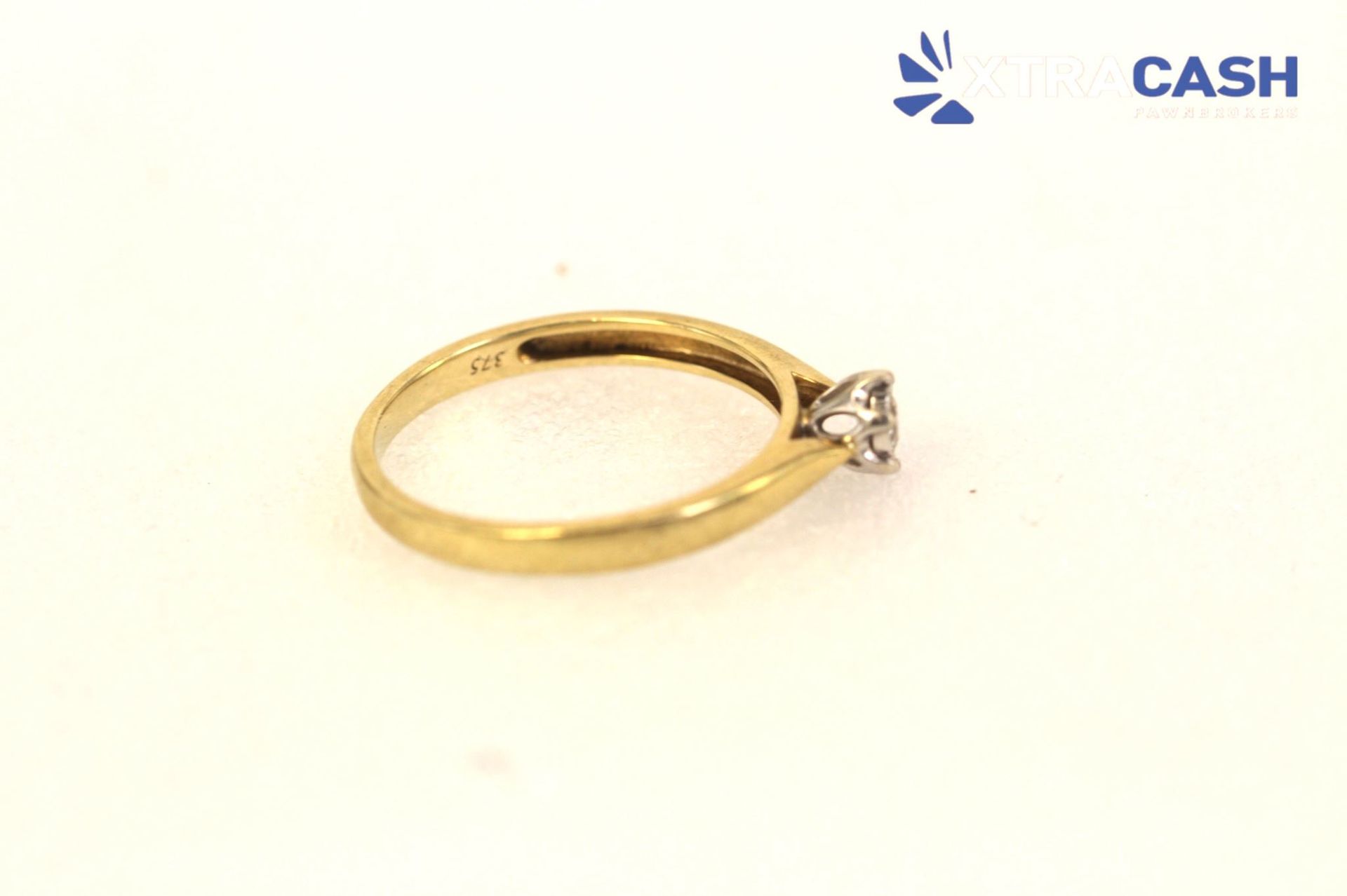 Gold ring with a small diamond setting on a white background