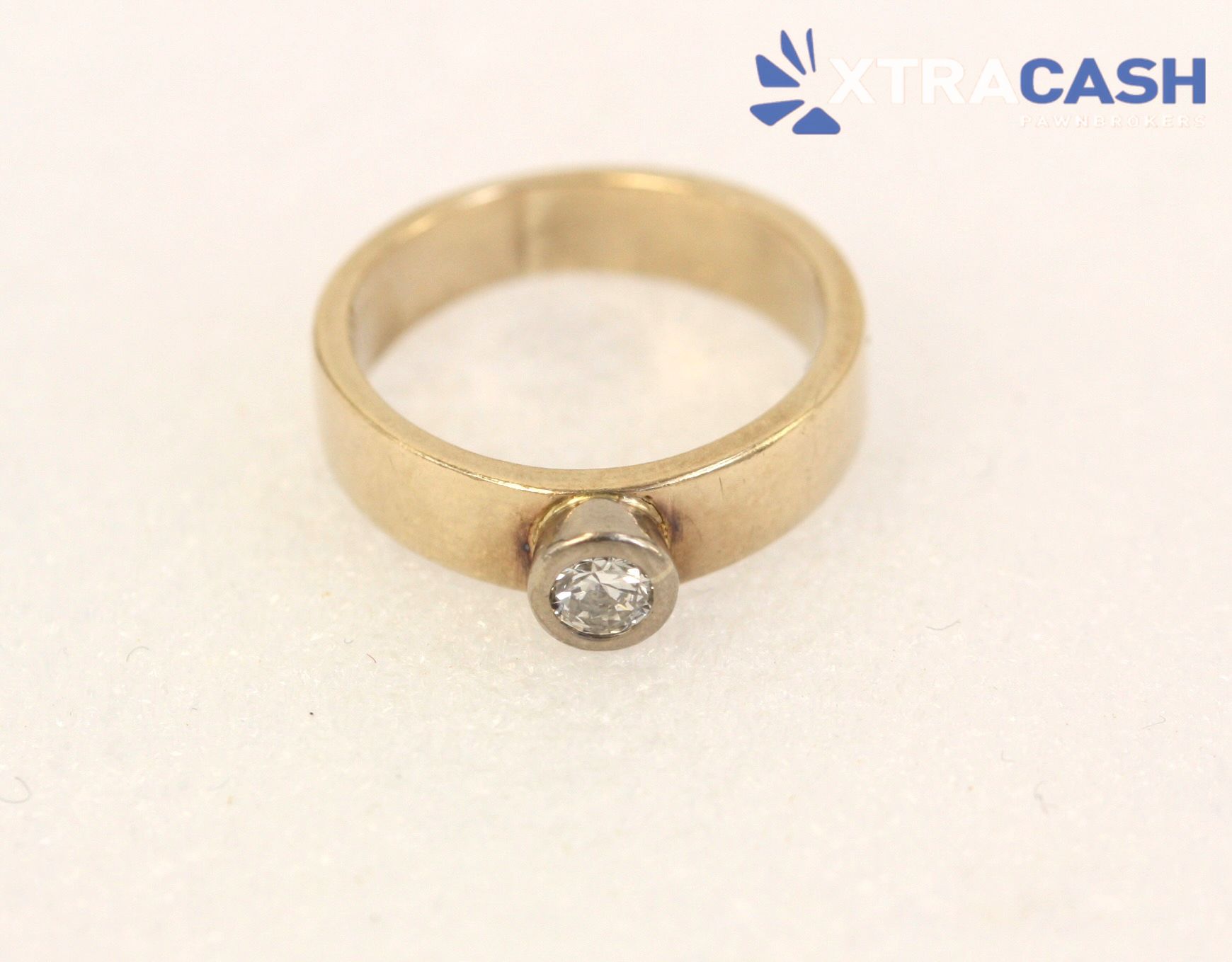 Gold ring with a round clear gemstone on a white background