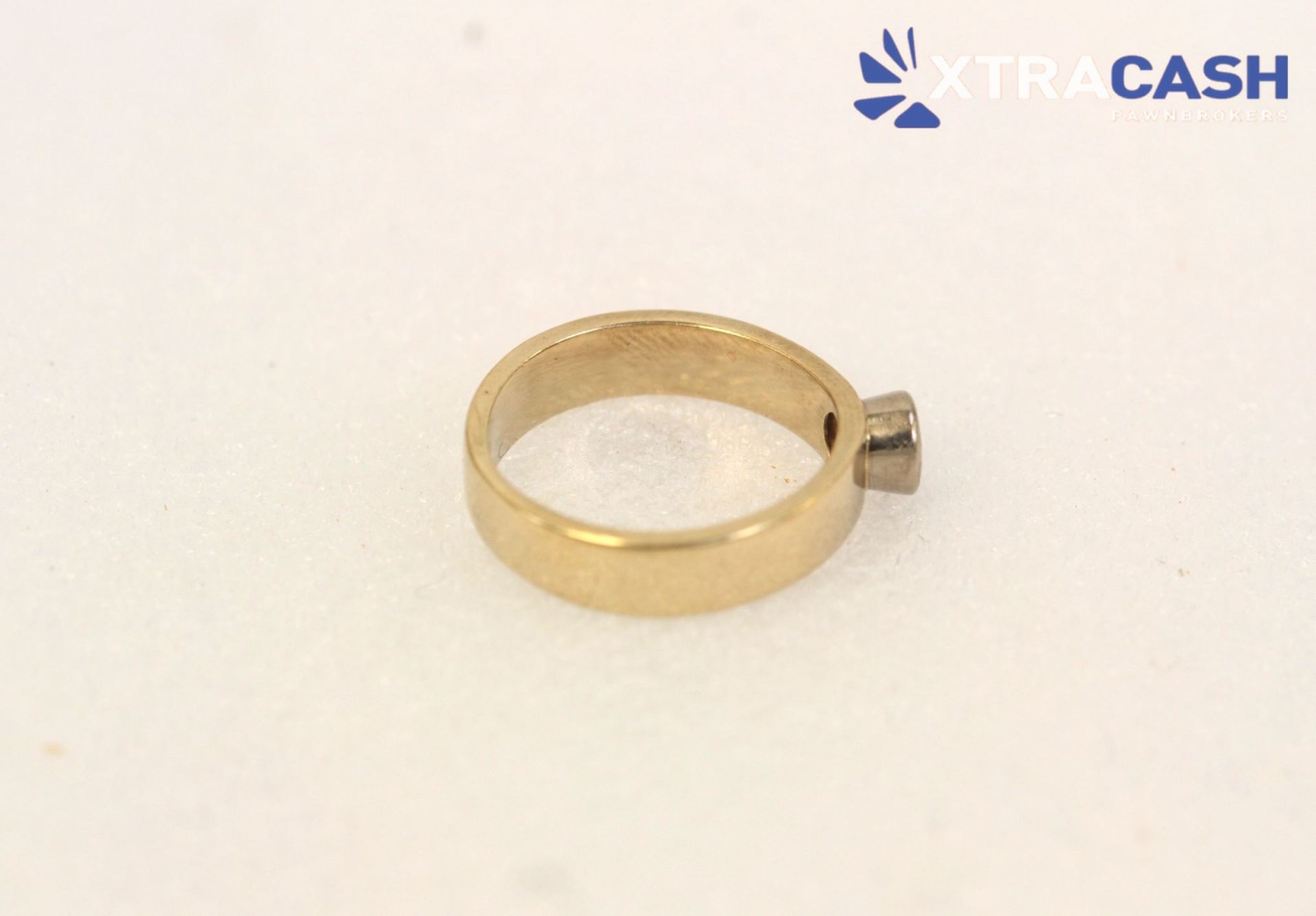 Gold ring with a round clear gemstone on a white background