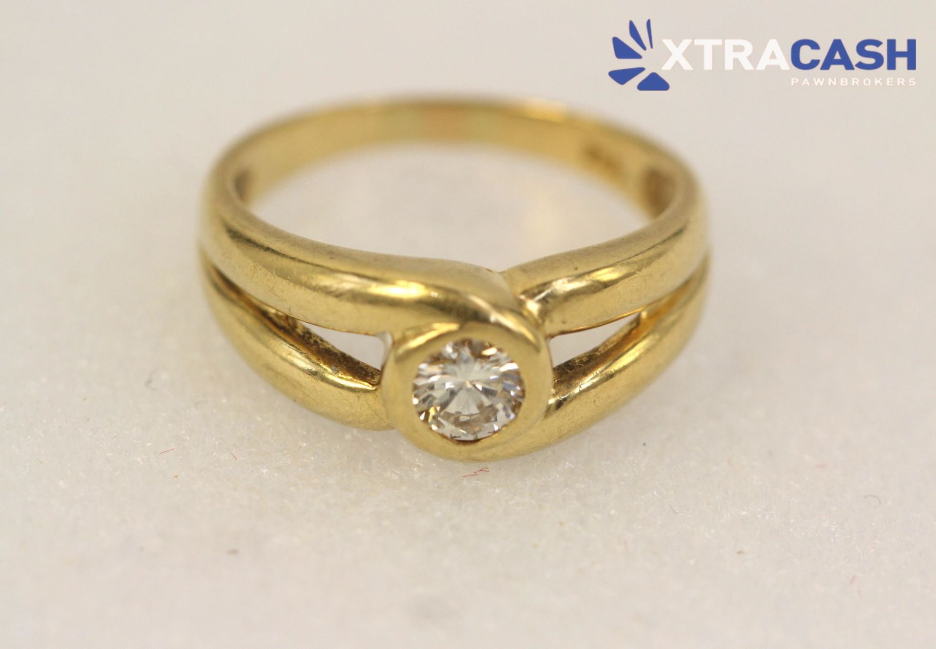 Gold ring with a central clear gemstone on a white background