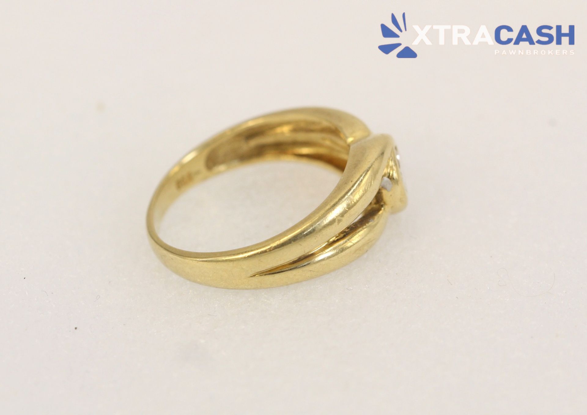 Gold ring with a central clear gemstone on a white background