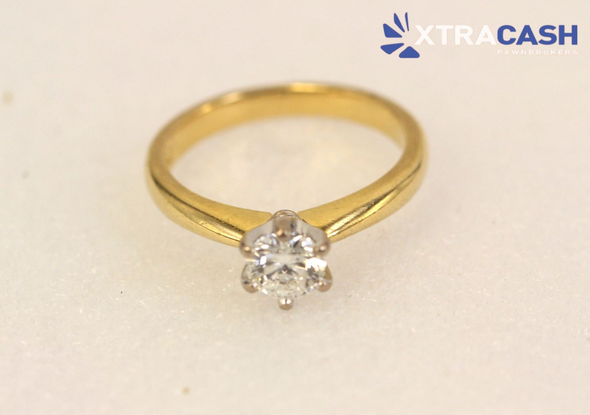 Two gold rings with a solitaire diamond and pavé band on a light background