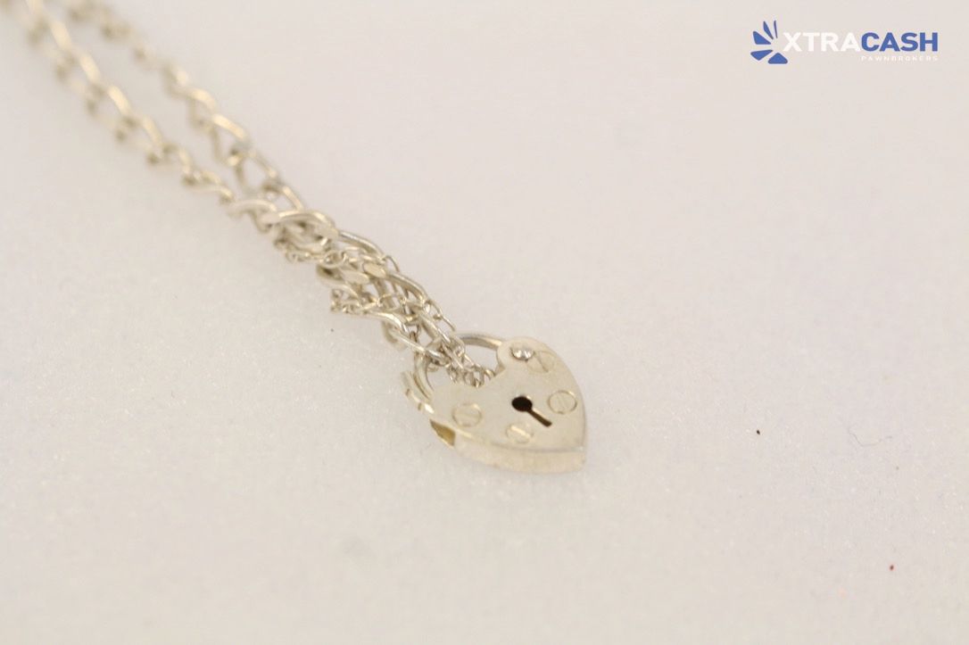 Silver necklace with heart pendant draped over a black display stand, with