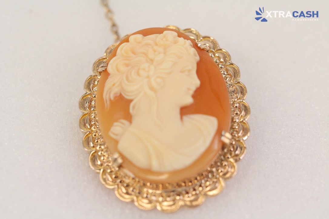 Gold pendant necklace with a cream cameo on a white background