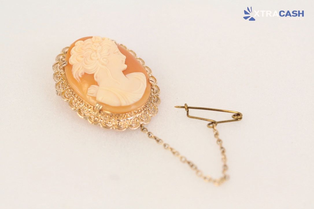 Gold pendant necklace with a cream cameo on a white background