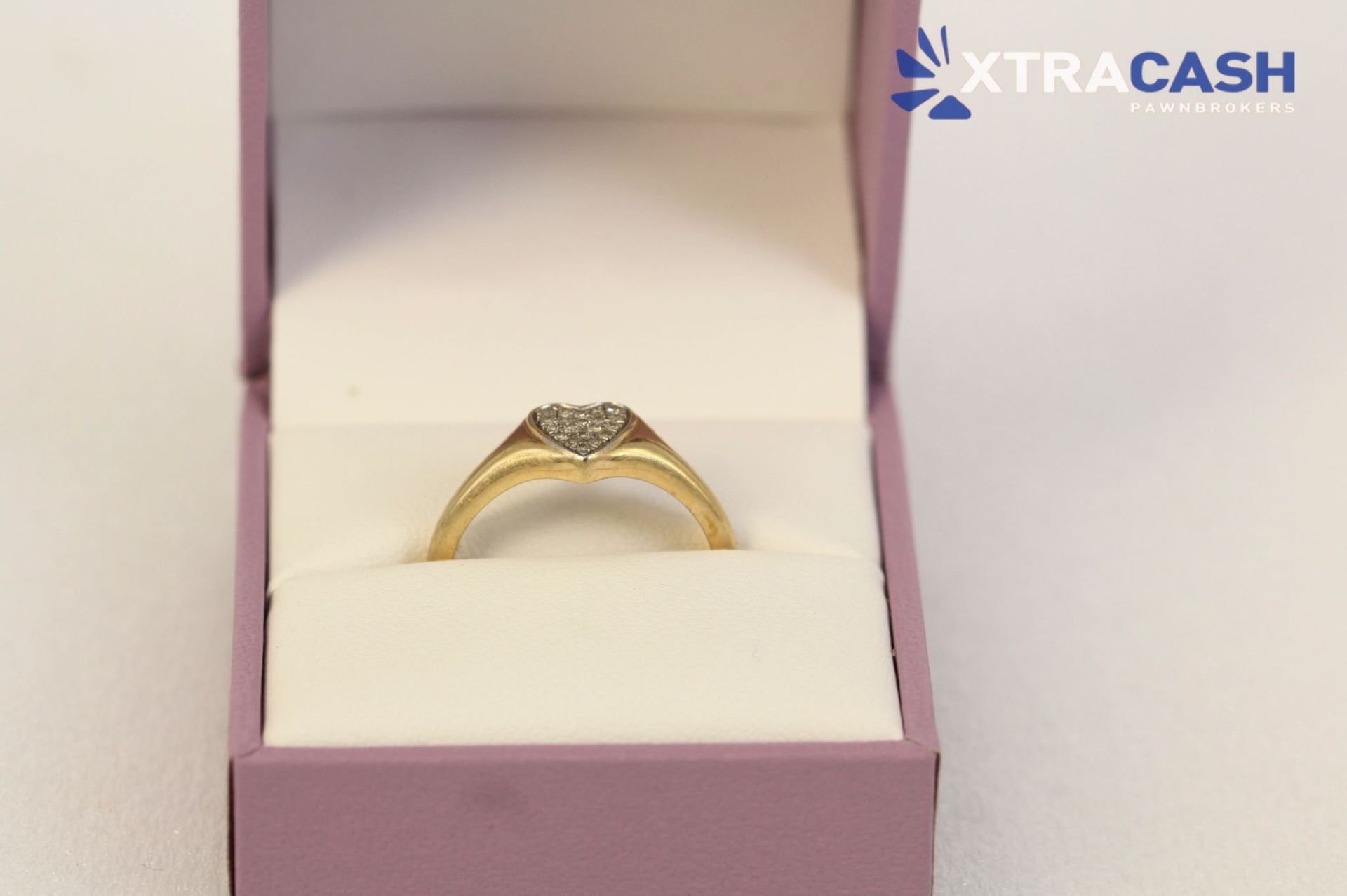 Gold ring in a pink jewelry box with a diamond on a soft white cushion