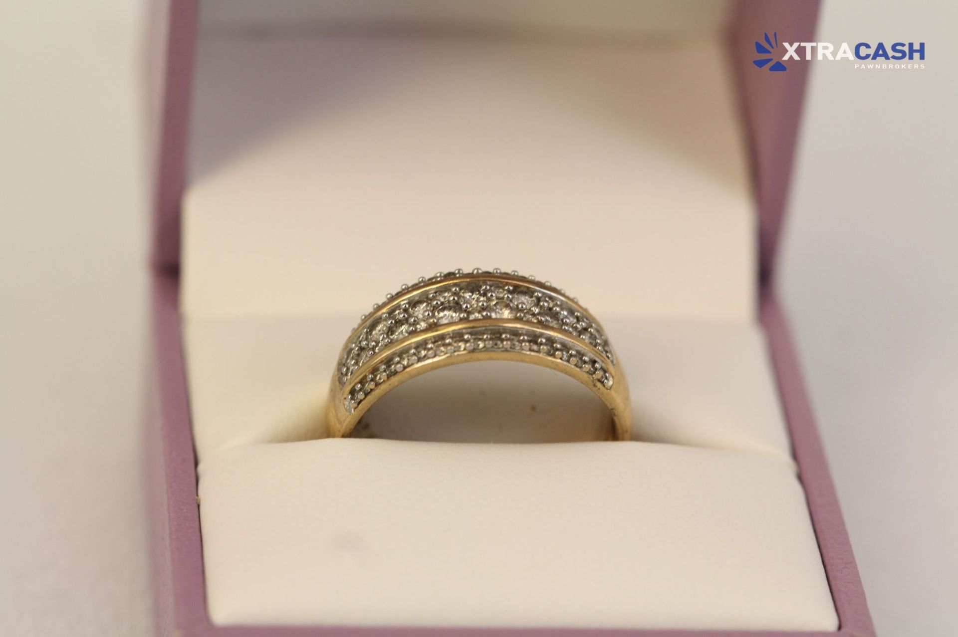 Gold ring with diamond accents displayed in a white jewelry box