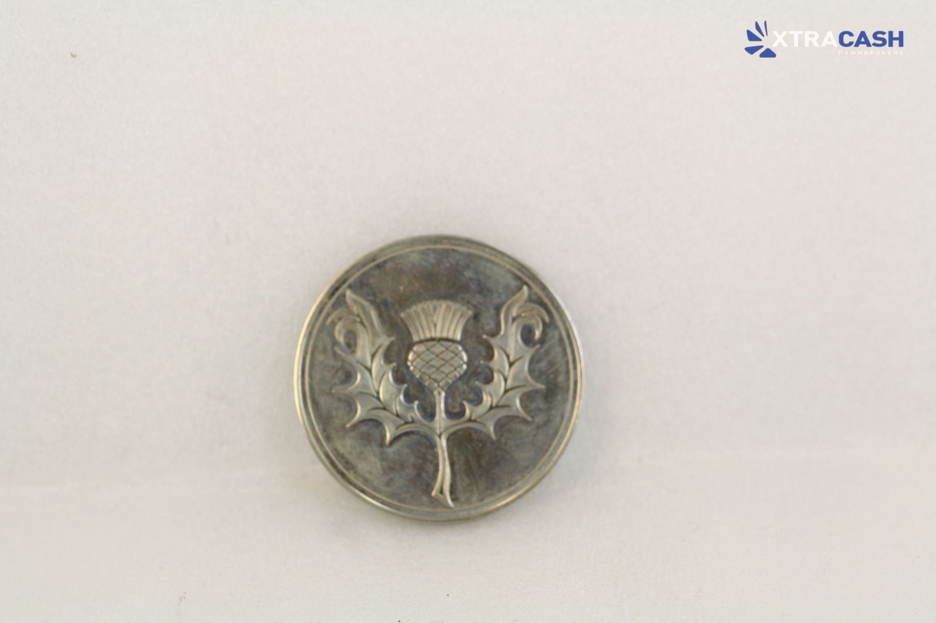 Silver coin with a dark winged emblem on a light background